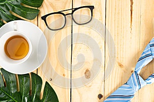Happy Father Day background concept with blue necktie, leaf, glasses and cup of tea on wooden background with copy space for text