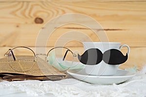 Happy Father Day background concept with and cup of tea, black mustache, glasses and newspaper on wooden background with copy