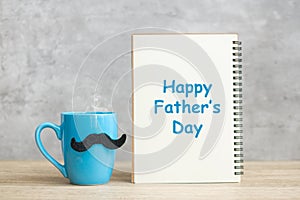 Happy Father day with paper notepad, Blue coffee cup or tea mug and Black mustache decor on table. International men day and