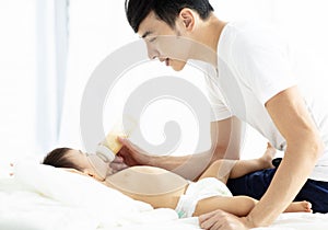 Happy father feeding baby from bottle