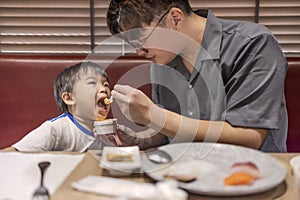 Happy father feeds her son in restaurant