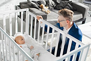 happy father in formal wear sitting near infant daughter