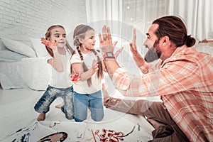 Happy father giving high five to his kids who are painting