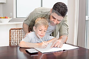 Happy father helping son with math homework at table