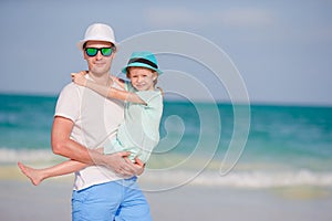 Happy father and his adorable little daughter at tropical beach having fun