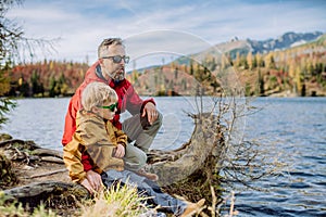 Happy father with his little son, resting near lake in mountains.