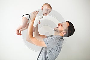 Happy father holding baby in hands over head isolated background