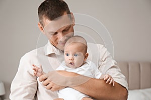 Happy father holding his cute baby at home
