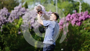 Happy father holding little baby-girl in arms and playing together in the park.