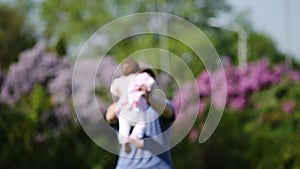 Happy father holding little baby-girl in arms and playing together in the park.