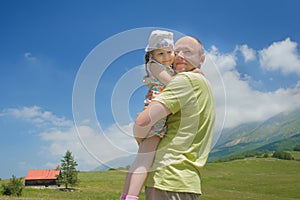 Happy father holding little daughter on his arms high Alpine meadow