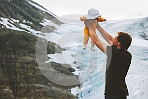 Happy father holding up baby travel together hiking in mountains