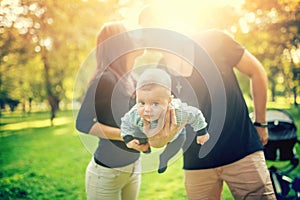 Happy father holds newborn baby on arm, kissing the mother of child. happy family in park, newborn kid and happiness