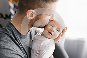 Happy father holds a newborn baby in his arms and kisses him