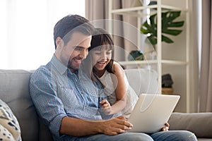 Happy father with kid laughing watching funny video on laptop