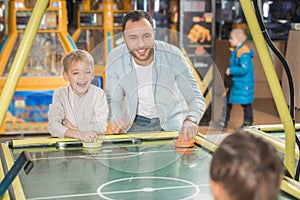 happy father with kids playing air hockey