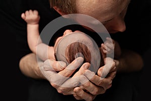 Happy father kisses his newborn. Baby sleeping soundly and peacefully. Concept of child care, feeling safe, parent love