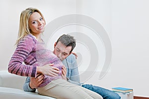 Happy father kissing the bump of pregnant woman