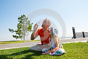 Happy father and a laughing small daughter enthusiastically inflate soap bubbles