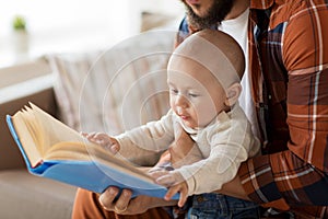 Happy father and little baby boy with book at home