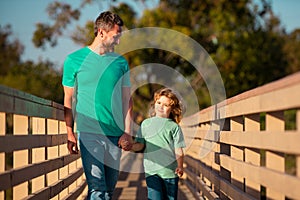 Happy father and little boy son walking in summer park. Father parenting his son.