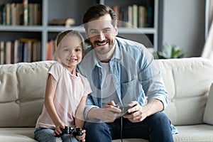 Happy father and little daughter playing video game at home