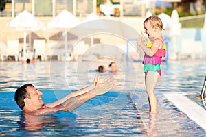 Happy father with little daughter in swimming pool