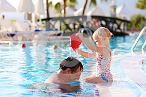 Happy father with little daughter in swimming pool