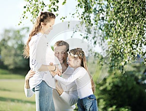 Happy father and little girl hugging her pregnant mother on a wa