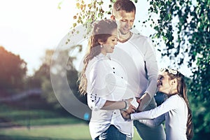 Happy father and little girl hugging her pregnant mother on a wa