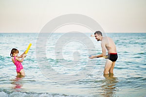 Happy father with little kid enjoying beach vacation with water gun, family vacation