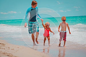 Happy father with little son and daughter play with water at beach