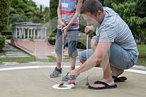 Happy father and  little son playing mini golf