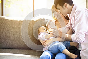 Happy father and mother feeding baby from bottle