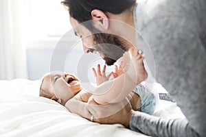 Happy father playing with adorable baby in bedroom