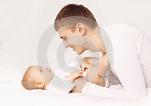 Happy father playing with baby at home lying on the bed
