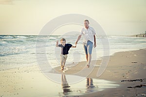 Happy father playing on the beach with little son running excited with barefoot in sand and water