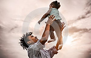 Happy father playing with his baby daughter during sunset time - Afro family having fun outdoor