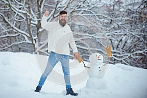 Happy father playing with a snowman on a snowy winter walk. Christmas Man and snowman on white snow background. Making