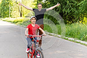 happy father rejoices that her daughter learned to ride a bike