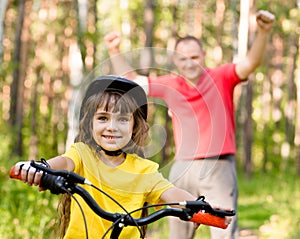 Happy father rejoices that her daughter learned to ride a bike