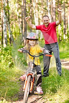 Happy father rejoices that her daughter learned to ride a bike