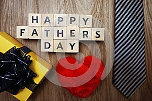 Happy Father`s Day alphabet letters with necktie gift box and red heart fluffy on wooden background