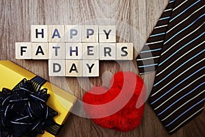 Happy Father`s Day alphabet letters with necktie gift box and red heart fluffy on wooden background