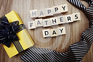 Happy Father`s Day alphabet letters with necktie and gift box on wooden background