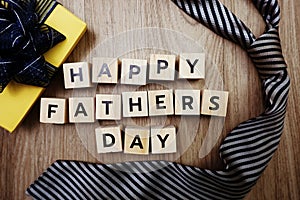 Happy Father`s Day alphabet letters with necktie and gift box on wooden background