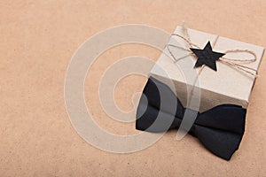 Happy Father`s Day Background. Beautiful retro style gift box and black bow tie on brown background. Fathers day.