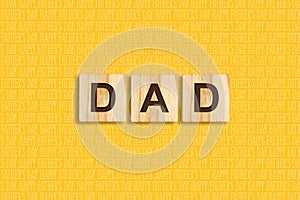 Happy father`s day background. Dad, Word, written on wooden blocks. Yellow background Congratulatory background