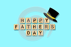 Happy father`s day background. Hat cylinder and the inscription on wooden blocks on a blue background. Congratulatory background