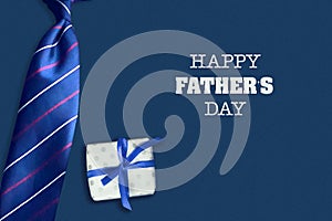 Happy father`s day background. The inscription on a dark background with a gift and tie. Congratulatory background